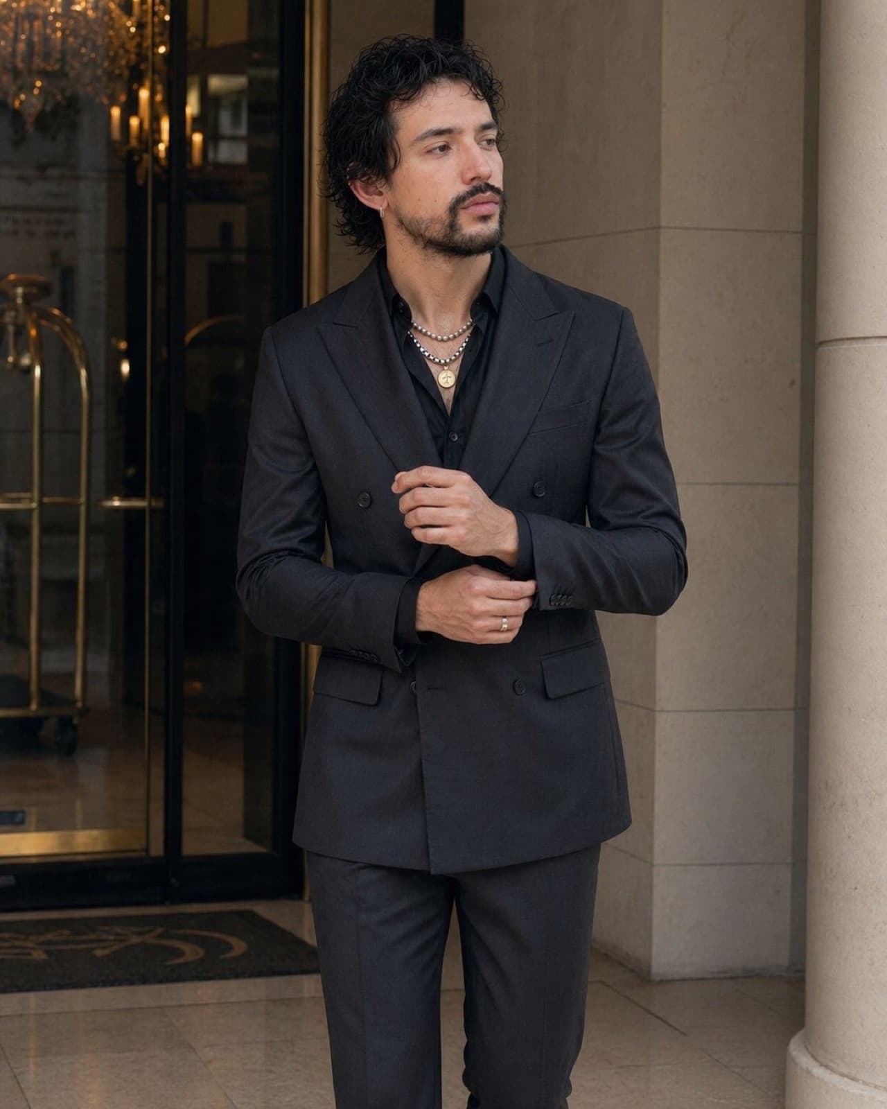 Alejandro del Palacio in a black double-breasted suit at a hotel entrance.